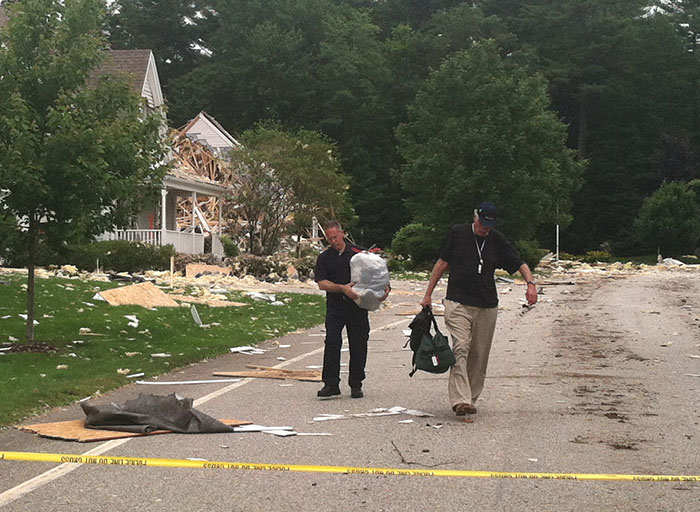 Resident Amory Houghton, right, gathers clothes and other belongings from his badly damaged unit on Gables Drive near the explosion site in Yarmouth. An unidentified Yarmouth police officer assists Houghton.