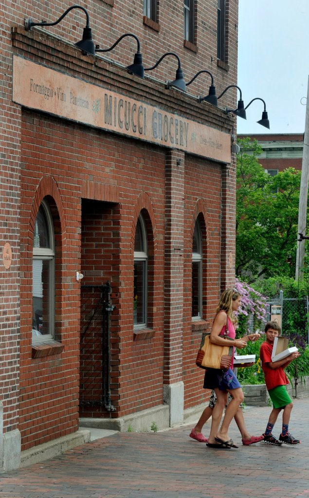 Customers leave Micucci's Grocery with their pizza slabs Monday. The grocery is still selling the slabs, luna bread and Italian pastries after baker Stephen Lanzalotta's departure.