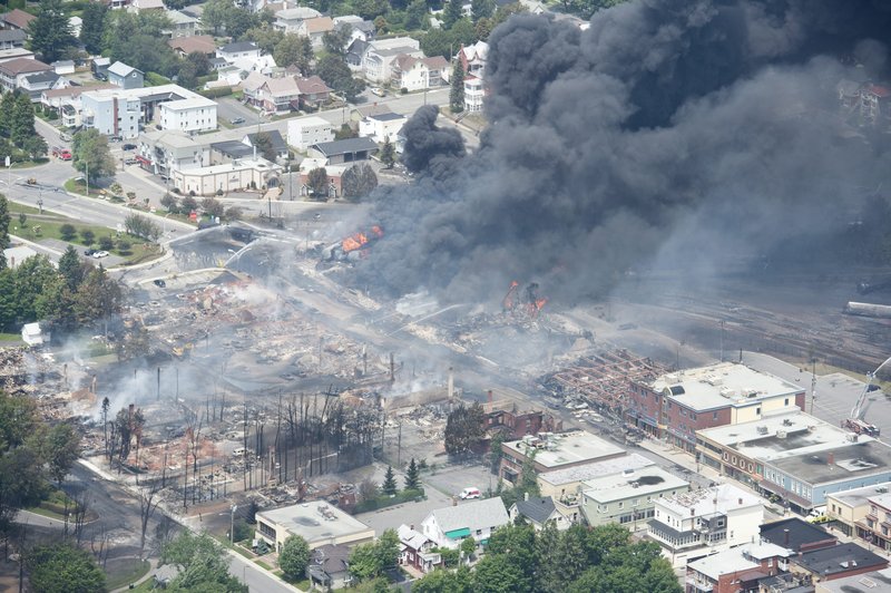 Smoke rises from railway cars that were carrying crude oil after derailing in downtown Lac Megantic, Que., Saturday, July 6, 2013. A large swath of Lac Megantic was destroyed Saturday after a train carrying crude oil derailed, sparking several explosions and forcing the evacuation of up to 1,000 people. (AP Photo/The Canadian Press, Paul Chiasson)