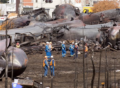 Workers stand before mangled tanker cars Tuesday, July 16, 2013, at the crash site of the train derailment and fire in Lac-Megantic, Quebec. The July 6 crash left 47 people dead and 40 buildings destroyed. (AP Photo/Ryan Remiorz, pool)