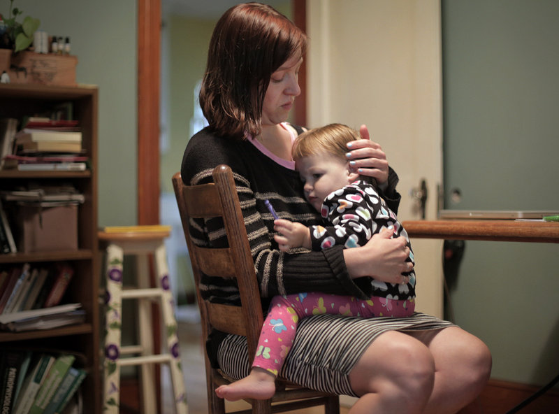 Erica Burkhart tends to her daughter Lumi Stone in her Portland home on Wednesday. Burkhart, a single mom attending graduate school, will buy her own insurance in the new marketplace opening Tuesday.