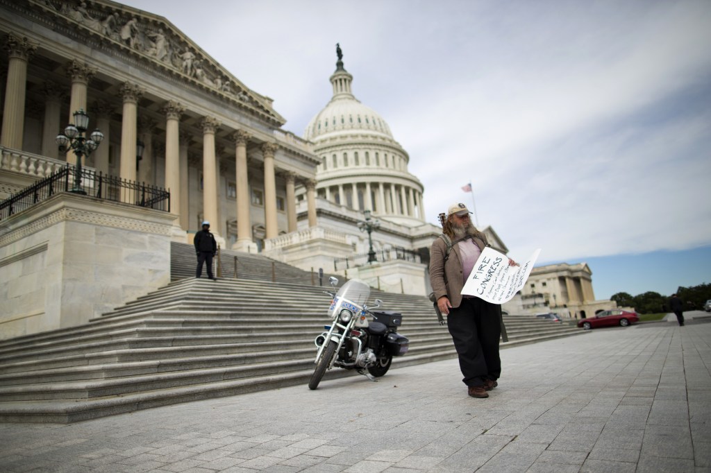 Rick Hohensee of Washington holds a “Fire Congress” sign Tuesday near the House steps on Capitol Hill in Washington during the second week of the partial government shutdown.