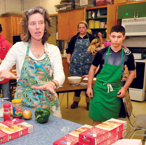 Skowhegan Area High School teacher Beth Scherpf speaks with students in the basic foods class last month. At right, student Jeremy Silva prepares to make pizza pockets.