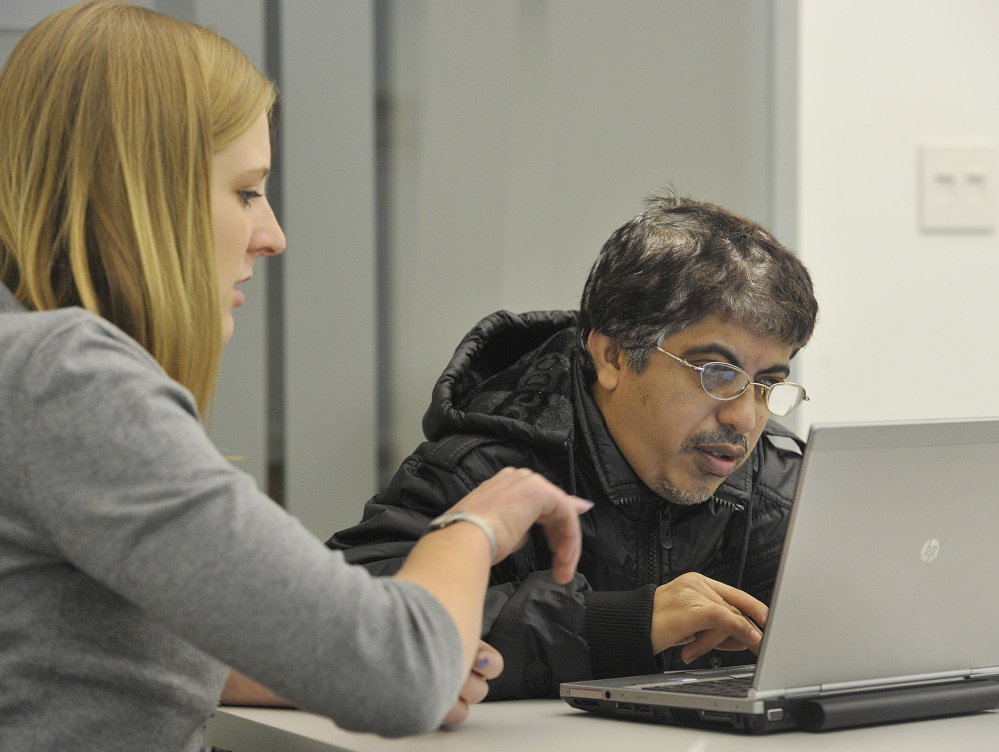 Libby Cummings, an outreach and enrollment specialist for the Portland Community Health Center, helps recent immigrant Tarunkumar Vaswani file his insurance request at the Portland Public Library on Friday.