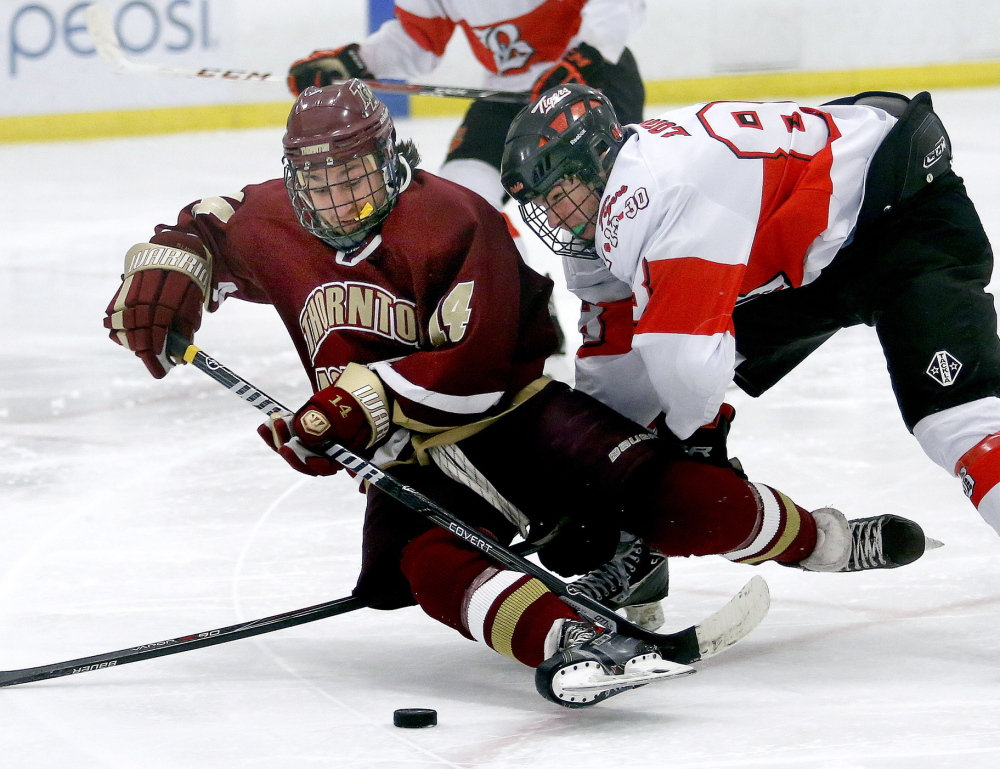 Drew Lavigne of Thornton Academy tries to control the puck while falling as Evan Loignon of Biddeford comes crashing into the play during the second period of Thornton’s 5-3 victory Tuesday night in a Western Class A quarterfinal at the Biddeford Ice Arena.