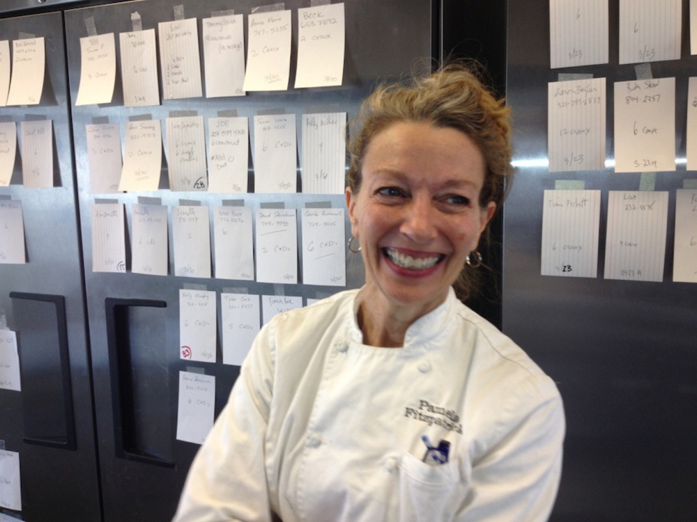 Pamela Fitzpatrick Plunkett poses in front of index cards that show orders placed for “C&Ds,” a cross between a croissant and a doughnut.