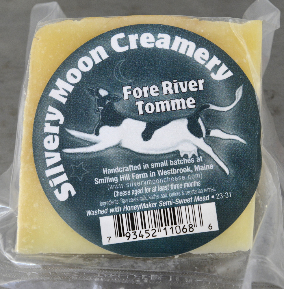 At top, cheese-maker Tyler Renaud breaks up curds and Kris Burleigh soaks them in steaming water as they make a Mexican oaxaca cheese at Silvery Moon Creamery in Westbrook. Above, a sample of the creamery’s Fore River Tomme cheese. Silvery Moon also makes a style of cheese based on a Manchego, but calls it Moonchego.