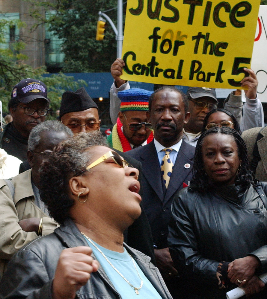 Dolores Wise, left, whose son Korey Wise was one of five youths convicted in the 1989 Central Park jogger case, sings “We Shall Overcome” at a 2002 rally in New York City. The city has settled a civil rights lawsuit by the five men exonerated in the case.