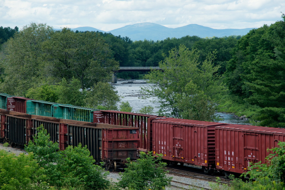 Box cars owned by the Montreal, Maine & Atlantic Railway sit idle next to the Pleasant River in Brownville in July 2013.