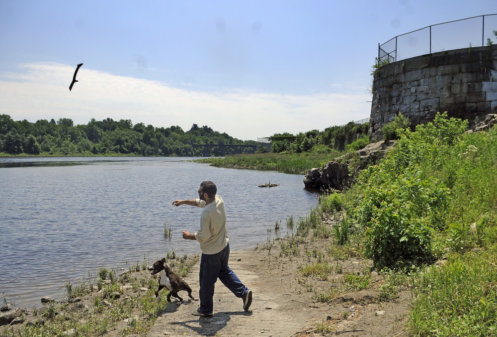 Mike Lehman of Windsor tosses a stick into the Kennebec River Monday for his dog at the site of the former Edwards Dam in Augusta.