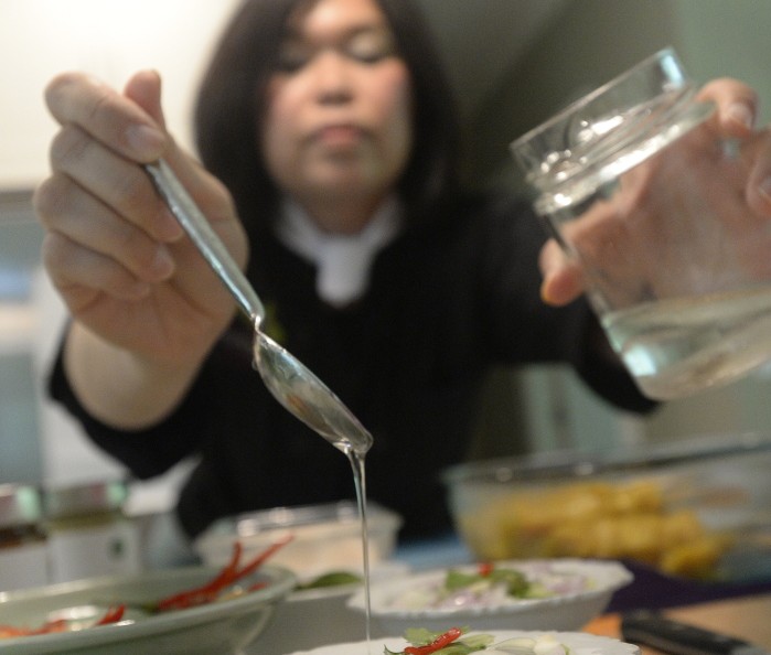 Watcharee Limanon drizzles dressing on a cucumber and shallot salad at her Thai Culinary Arts Studio in Yarmouth. Limanon has introduced a line of Thai sauces that are available at more than two dozen local stores and also plans to offer cooking classes, dinner parties and, eventually, culinary adventures abroad. 