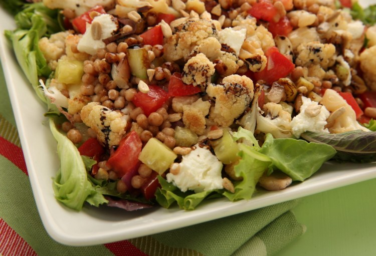 A colorful couscous salad with roasted cauliflower and dijon dressing will be a welcome surprise at a potluck gathering.