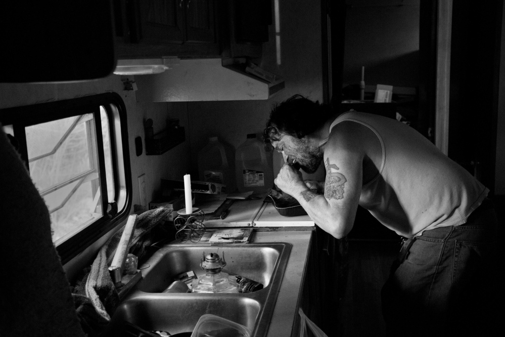 Ira Gilbert, an unemployed Passamaquoddy tribal member, bites into a frozen Salisbury steak dinner that he shared recently with his three dogs at his rustic home in Indian Township. Poverty persists on the reservation; a Harvard University study suggests that economic success among American Indians is linked to a stable rule of law.