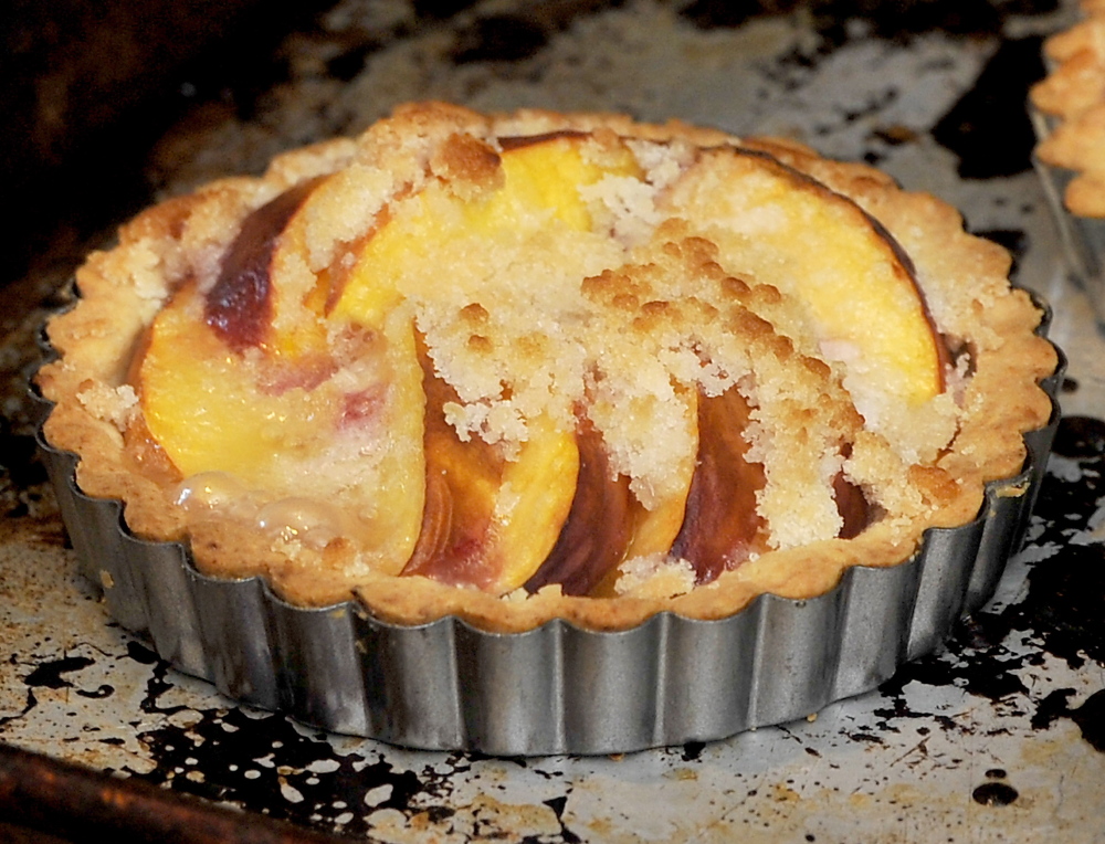 Christine Burns Rudalevige pulls a peach tart from the oven.
Gordon Chibroski/Staff Photographer