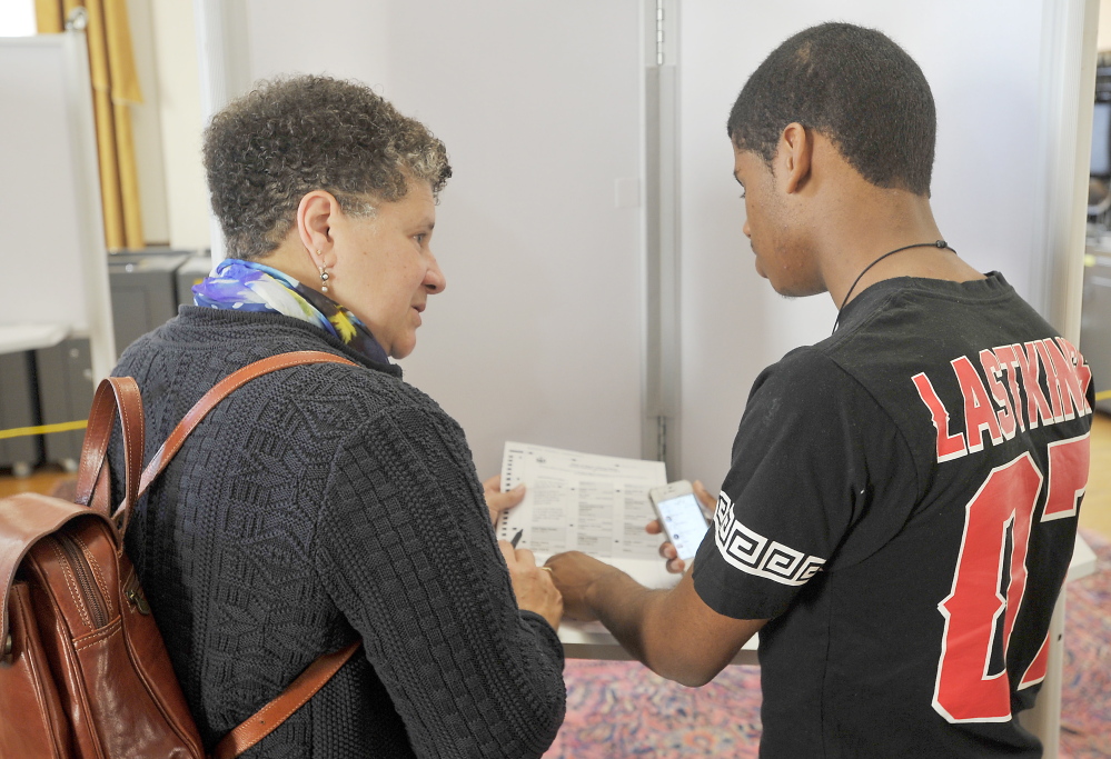 Sharon Talbot Verloo explains the voting process to her son, Washington Verloo, as she fills out her absentee ballot at Portland City Hall in October 2014.