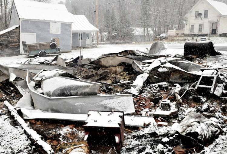 The home of Rick and Tina Belanger lay in blackened ruins in front of the building that housed the Caratunk Post Office and apartments on Monday. Fire broke out Sunday and destroyed the home, another nearby home and garage and did serious damage to the post office property. David Leaming/Morning Sentinel Staff Photographer