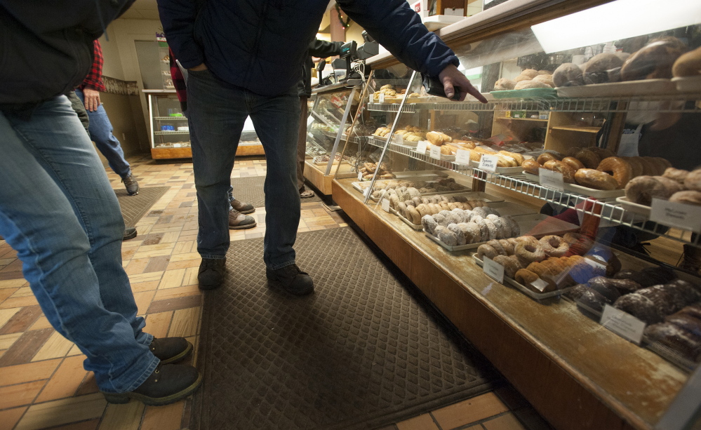 Customers point out the doughnuts they want at Hillman’s Bakery in Fairfield on Tuesday morning. Daryl Buck has baked the doughnuts and pastries at Hillman’s on and off since he was 13. Wednesday was Buck’s last day making doughnuts and pastries at Hillman’s.