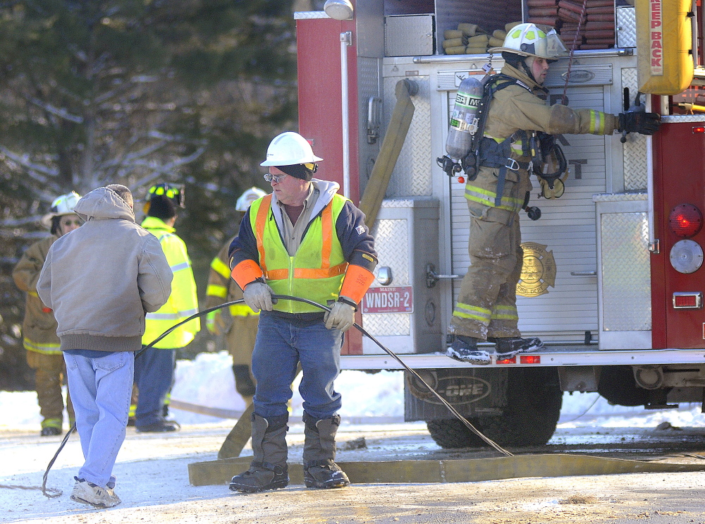 Central Maine Power lineman Wayne Piper collects an electrical wire he disabled after it fell upon a fire engine at farmhouse fire on Route 105 in Somerville on Sunday. After the hot line burned off the farmhouse and landed on an engine, fire crews had to wait for the utility to arrive and shut off the power before putting water on the blaze.