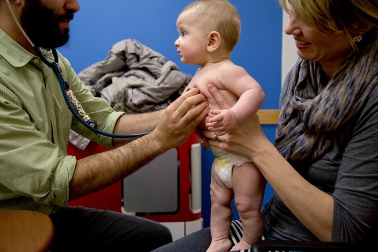 Dr. Andrew Tenenbaum of InterMed Pediatric Care in South Portland examines 6-month-old Alexander Hickey, held by his mother, Bethany, of South Portland, during a doctor’s visit Thursday that included a meningitis vaccination for the baby. A recent outbreak of measles in California “has made me extra sure to be current on everything,” Hickey said.