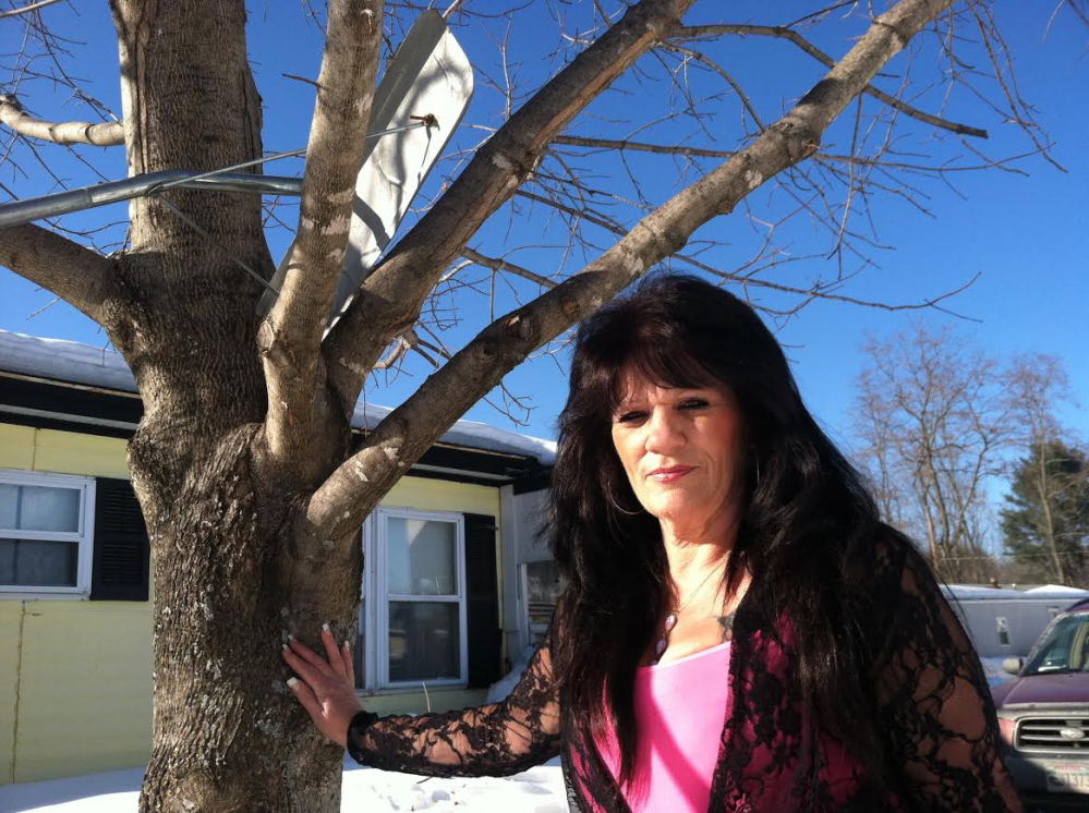 Rhonda West stands by the tree in her Oakland yard where she was attacked by a stray cat.