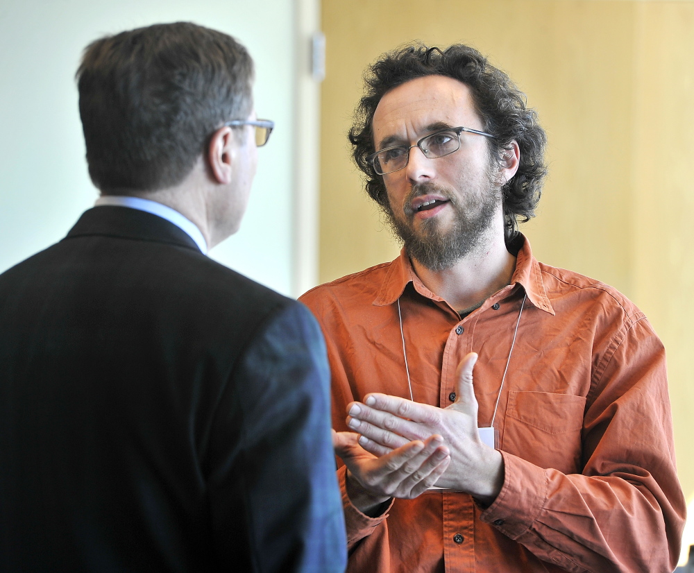 Jonah Fertig, right, specialist in cooperative ventures, speaks with a USM official before a conference on local foods.