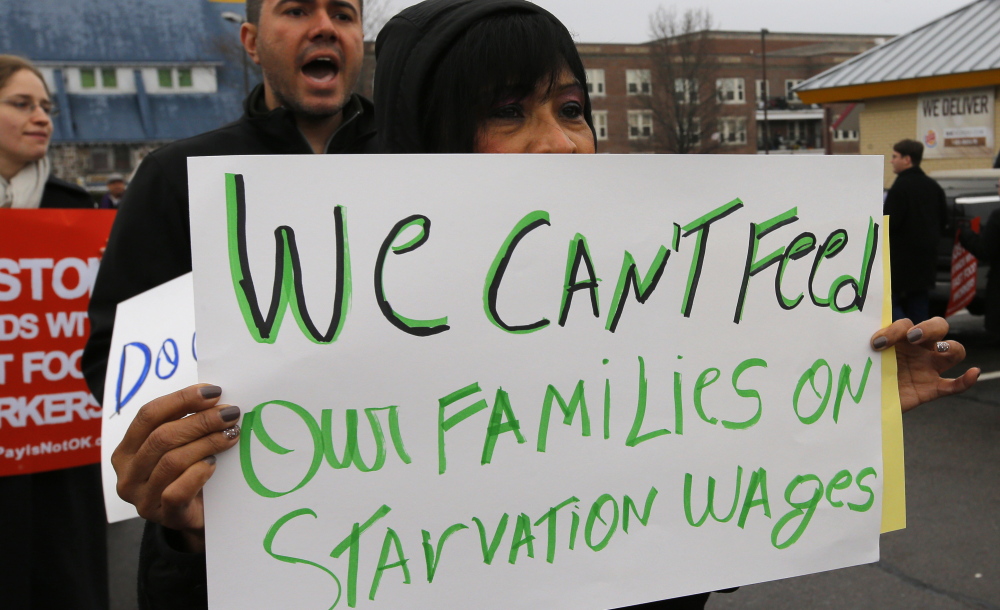 Gladys Jimenez of Boston holds a sign during a demonstration in support of higher minimum wages for fast-food workers. Low-wage Maine workers also are hoping for an increase this year.