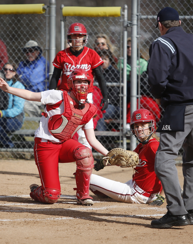 South Portland catcher Kiley Kennedy and Kaleigh Scoville of Scarborough wait for the call on a close play at the plate Friday. Scoville was called out, but Scarborough won the mutual season opener, 26-0 in five innings.