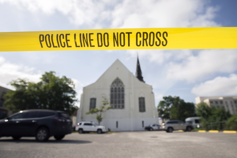 Police tape surrounds the parking lot behind the AME Emanuel Church as FBI forensic experts work the crime scene Friday. 