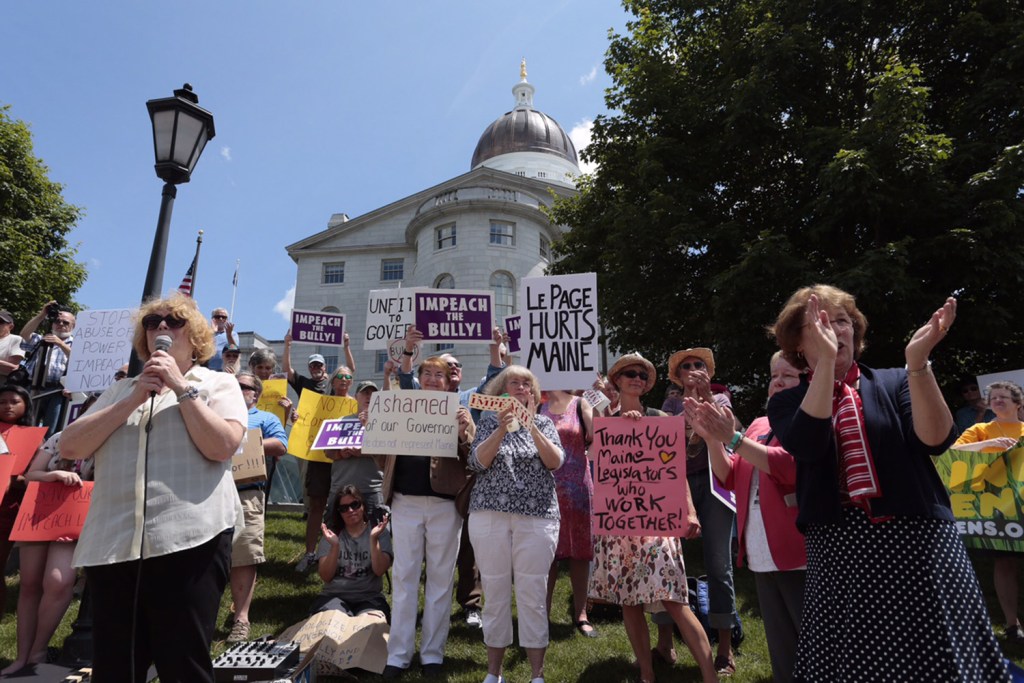 Gov. Paul LePage holds a broom during a rally of about 50 people who supported the governor's veto of the $6.7 billion state budget. The governor said the broom represented his conviction that he had been re-elected to clean up in Augusta. Screen image from WCSH-TV video