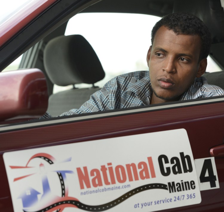 Cab driver Ahmed Issack, waiting for a fare at the Portland jetport, says Uber and Lyft drivers should have to go through the same permitting process that he does.