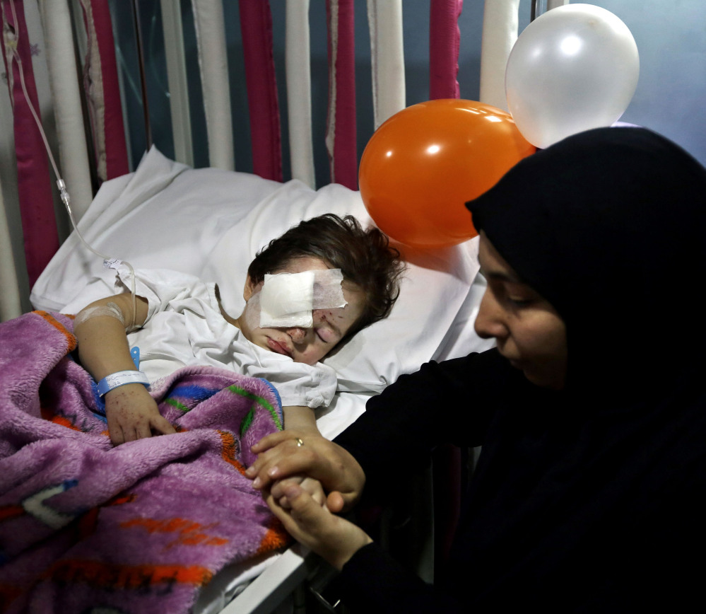 Adraa Taleb holds the hand of her 3-year-old cousin, who was wounded last week in suicide bombings in a Beirut suburb that killed at least 43. Some ask why the attacks there didn’t get the same attention as those in Paris.