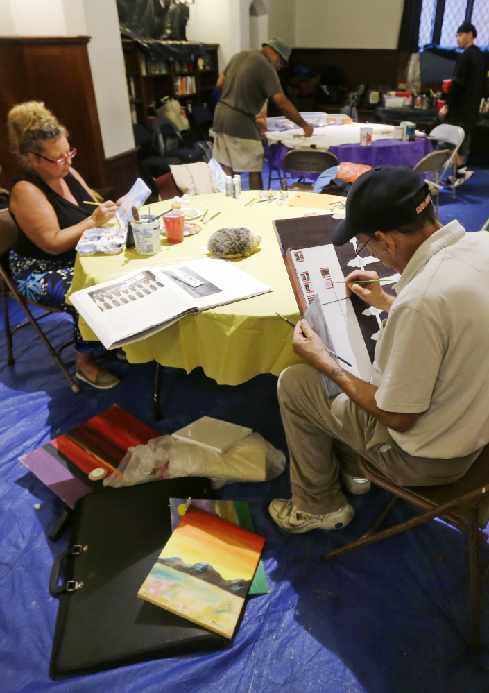 Homeless artists Romani Berlekov, left, and Frank Brescia paint at the Emmanuel Episcopal Church in Boston during a Wednesday painting session.