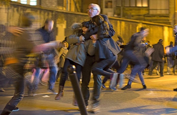 A man carries two children after panic broke out among mourners who payed their respects at the attack sites at restaurant Le Petit Cambodge (Little Cambodia) and the Carillon Hotel in Paris, Sunday. Thousands of French troops were deployed around Paris on Sunday and tourist sites stood shuttered in one of the most visited cities on Earth. The Associated Press