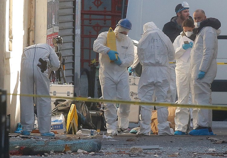 Forensics experts examine the scene in Saint-Denis, near Paris, on Wednesday. A woman wearing an explosive suicide vest blew herself up as heavily armed police tried to storm an apartment there where the suspected mastermind of last week's attacks was believed to be holed up.