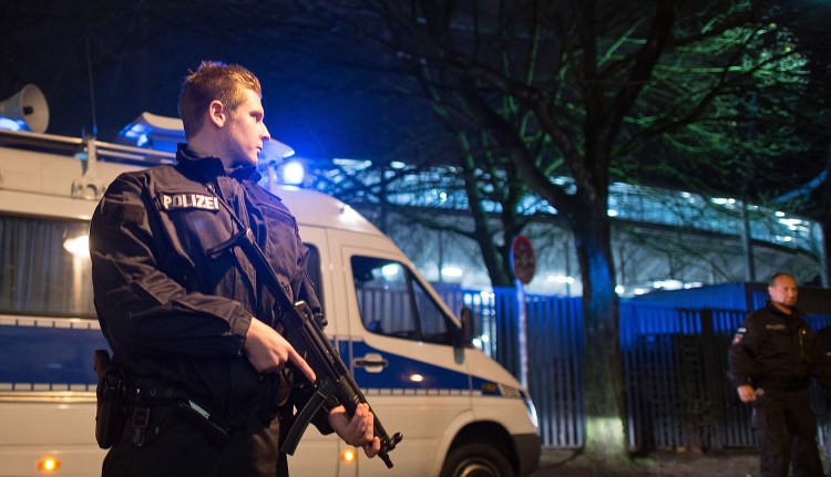 A police officer carries a submachine gun outside the HDI-Arena in Hanover, Germany, on Tuesday. The exhibition soccer match between Germany and Holland was canceled at short notice and the stadium was evacuated after a suspicious object was found.