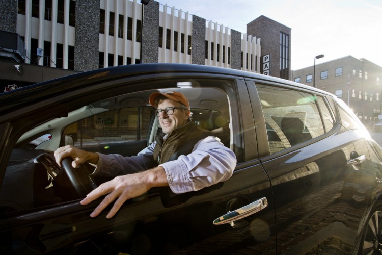 Don Tuski, (cq) president of MECA, poses for a portrait with his electric car, a Nissan Leaf, on Free Street in Portland Wednesday, November 25, 2015. Gabe Souza/Staff Photographer