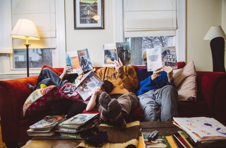 Alex Irvine, center, with his children Emma, 14, left, Abraham, 5, center left, and Ian, 14, right, all holding some of their favorite Star Wars graphic novels and novels  in South Portland, ME on Wednesday, December 2, 2015. Irvine is a science fiction writer, along with a Star Wars fan, and he’s passed down a love for both to his three children.