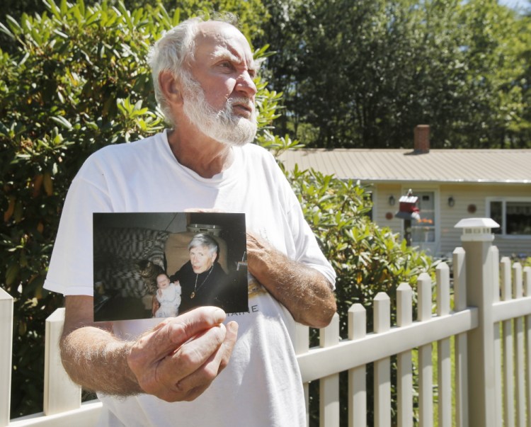 Robert Douglas displays a photo from around 1998 that shows his late wife, Rita, as she holds their granddaughter. Douglas is skeptical that the sun blinded the driver who struck his wife, but said, ‘I have to take the word” of police.