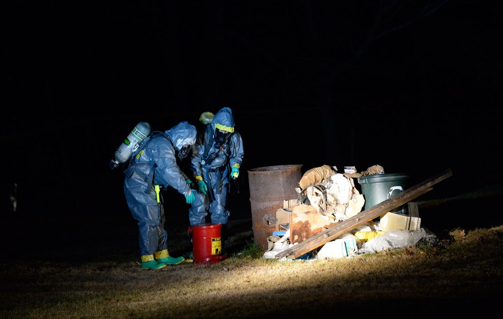 Members of the Maine Drug Enforcement Agency go through a burn pile on the property of 125 Old Thompson Road in Buxton. They said they discovered three "one-pot" bottles used to make methamphetamine in the pile Tuesday.