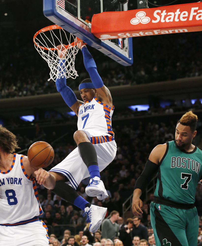 Knicks forward Carmelo Anthony hangs from the rim after a dunk, as Celtics center Jared Sullinger watches in first half Tuesday night. Anthony later left the game with a sprained ankle.