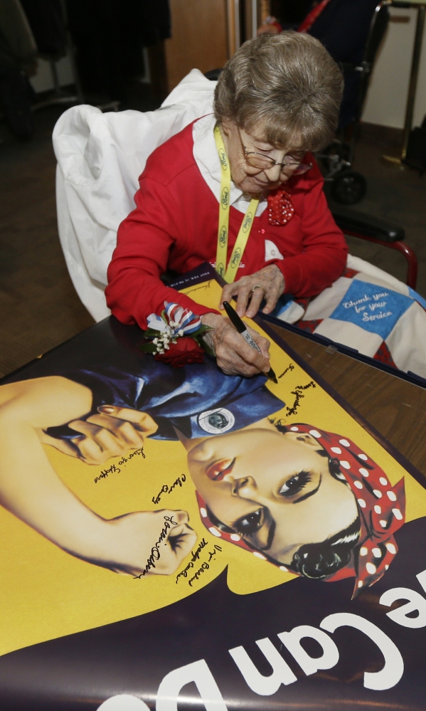 Frances Reeck signs a Rosie the Riveter poster in Washington. She was one of about 30 World War II  Rosies honored with rock-star treatment Tuesday in the capital.