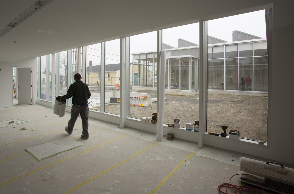 Workers at the new Center for Maine Contemporary Art building in downtown Rockland. The center is scheduled to open in June. Below: One of the architecturally unique spaces in the gallery.