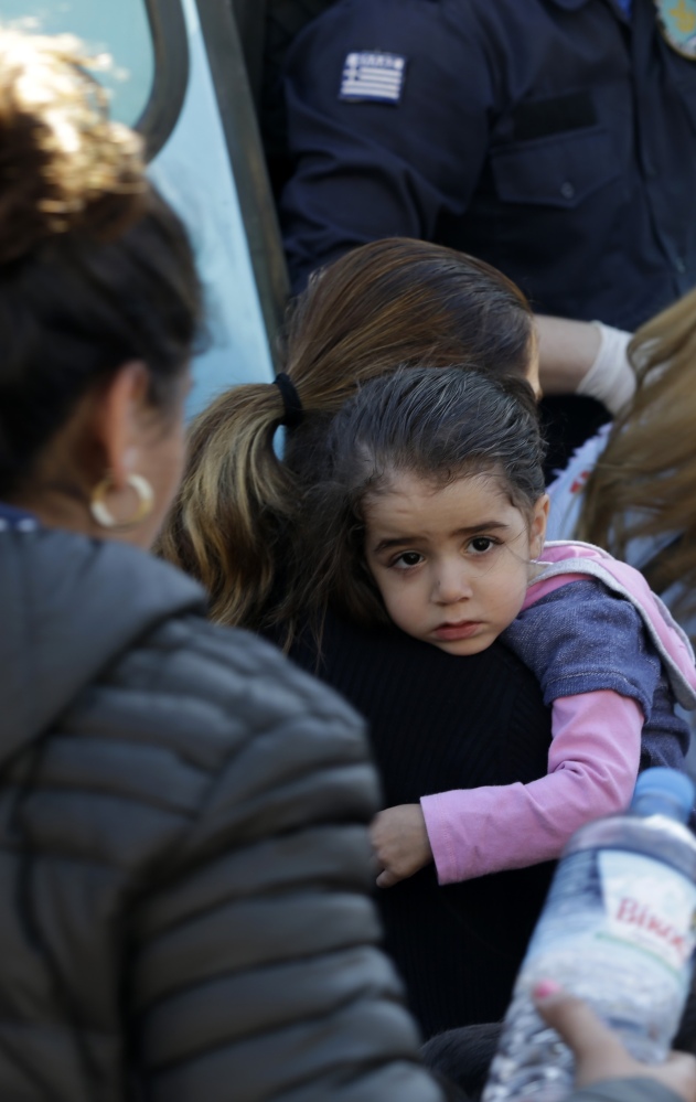 Syrians board a bus to be transferred from the Athens port of Piraeus to a refugee camp in March.