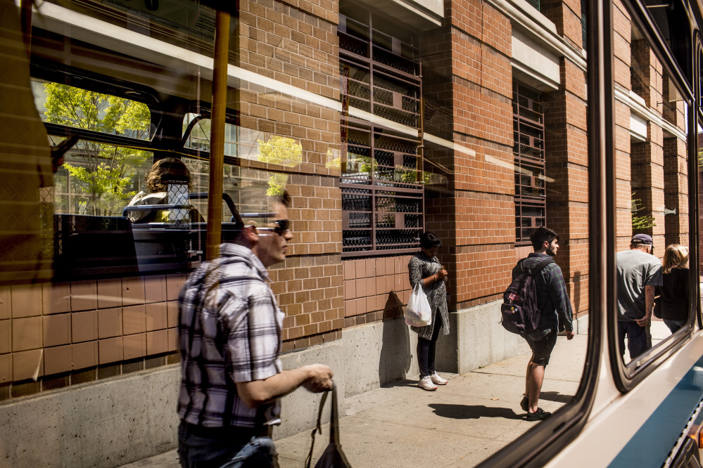 Riders are reflected in the windows of a Metro bus as they wait to board. The launches of a real-time ride-tracking service and express bus service to Freeport are part of a broader push to make mass transit more efficient and relevant to people living in the Portland area.