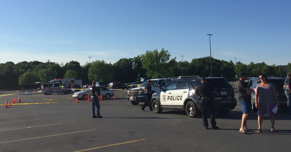 Crime scene tape surrounds a Volkswagen Jetta on Sunday evening in a parking lot at the Wal-Mart store in Augusta as police officers look for evidence after a report of shooting at the site.