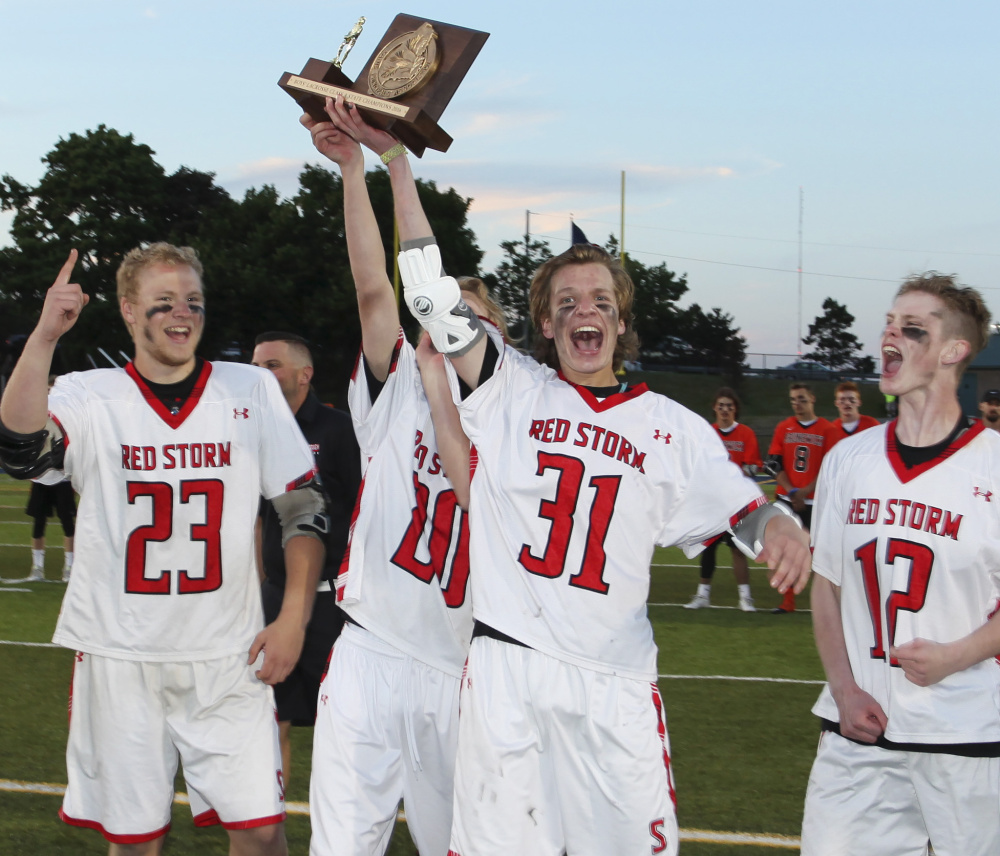 Scarborough's Cam Nigro, center, hoists the trophy and is joined by his teammates after the Red Storm beat Brunswick for the Class A state championship at Fitzpatrick Stadium on Saturday.