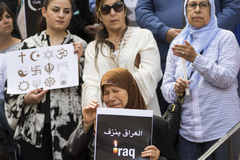 Hamdiyah Alwakeal, center, breaks down in tears during the vigil. Alwakeal says her 17-year-old nephew, Ali Alwakeal, was killed in the attack. 
