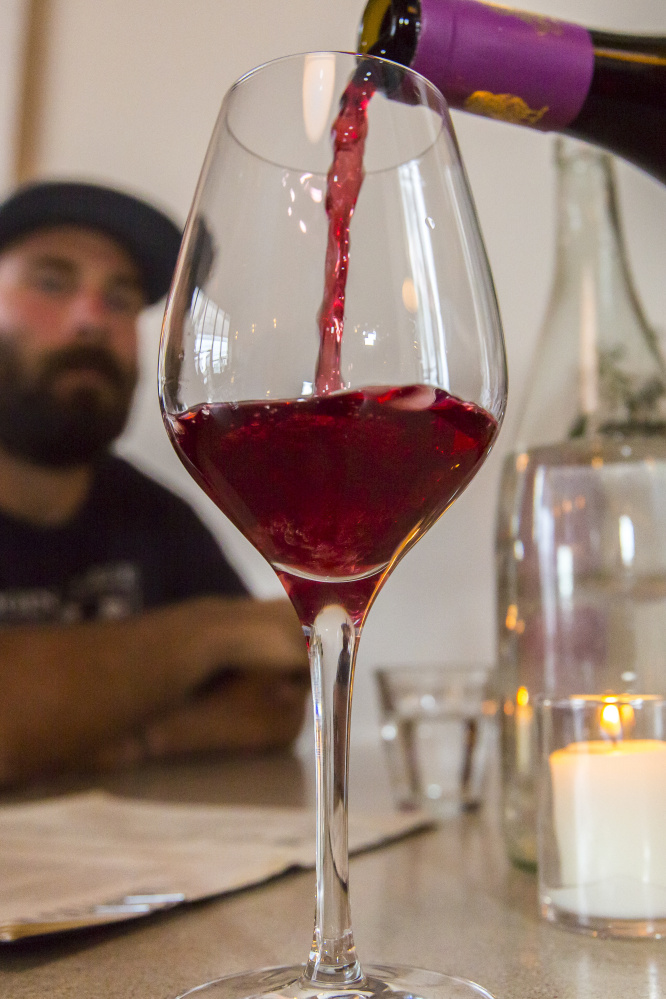 Customer Sam Gilbert watches as Domaine des Sablonnettes' "Le Bon Petit Diable" – a 2013 Cabernet Franc – is poured at the Drifters Wife bar.