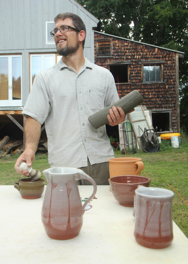 Jon Lamarche holds some processed pottery clay in front of some his works behind Wayne Village Pottery. The Saunders' family, which runs the pottery business, was hoping to dig up 40 tons of clay on Saturday and have enough to last five to 10 years until the next dig. Lamarche owns the nearby Old Firehouse Farm gift shop and cafe but helps out at Wayne Village Pottery in exchange for pottery clay.