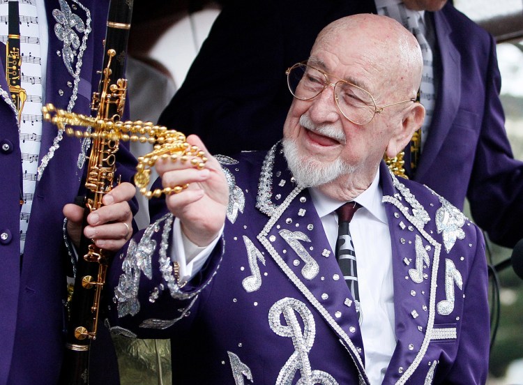 Pete Fountain tosses beads to a reveler from a float as his Half-Fast Walking Club marches down St. Charles Avenue in New Orleans on Mardi Gras Day in 2011. (AP Photo/Patrick Semansky)